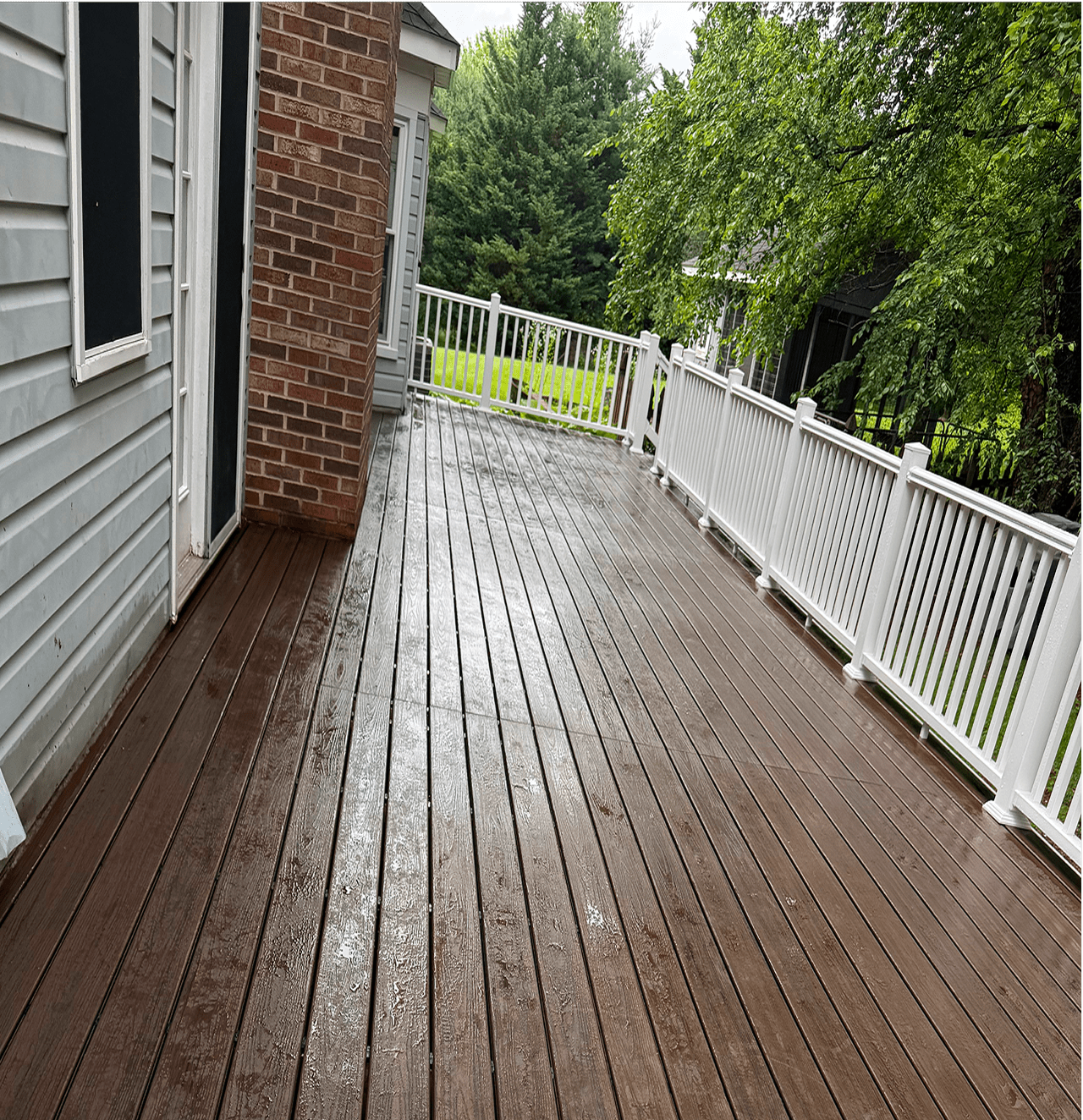 Wet wooden deck with white railing.