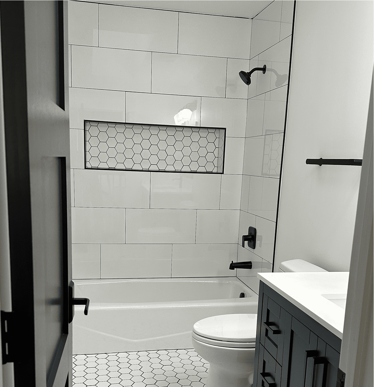 Modern bathroom with white tiles and fixtures.