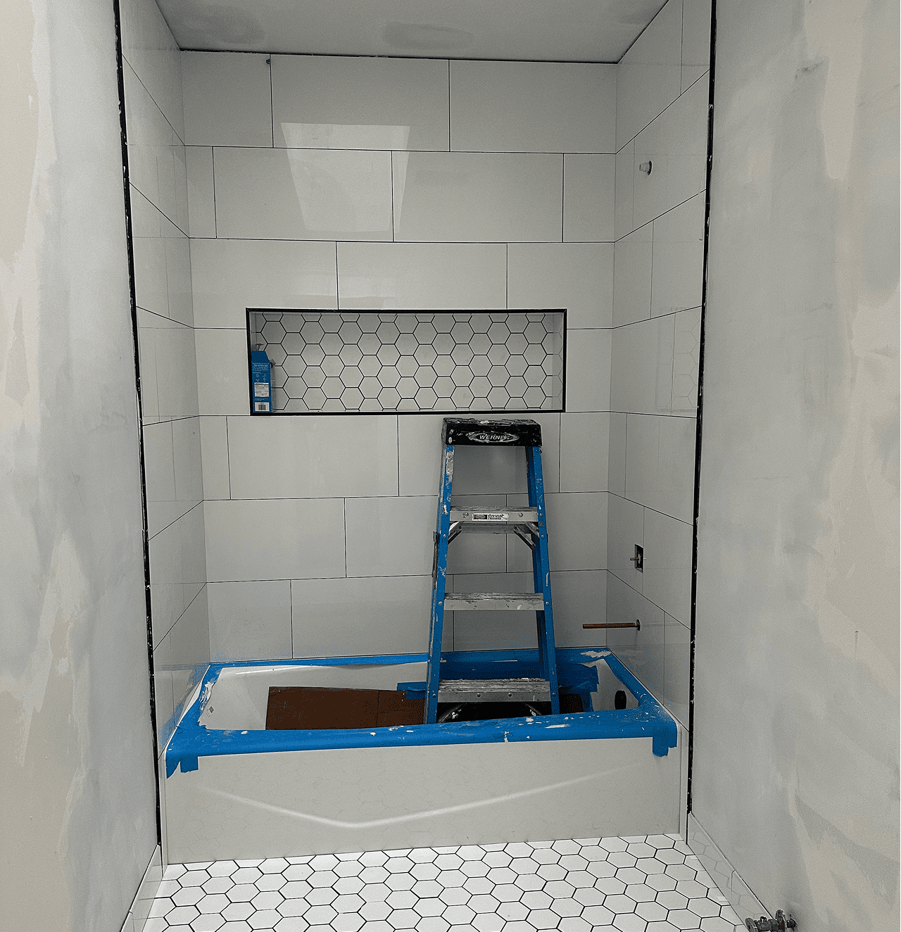 Bathroom under renovation with ladder and tiles.